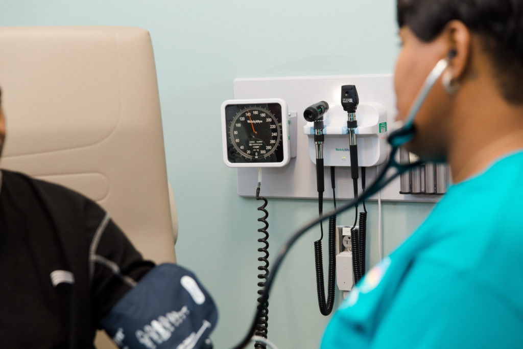 a female nurse checks the blood pressure of a male patient