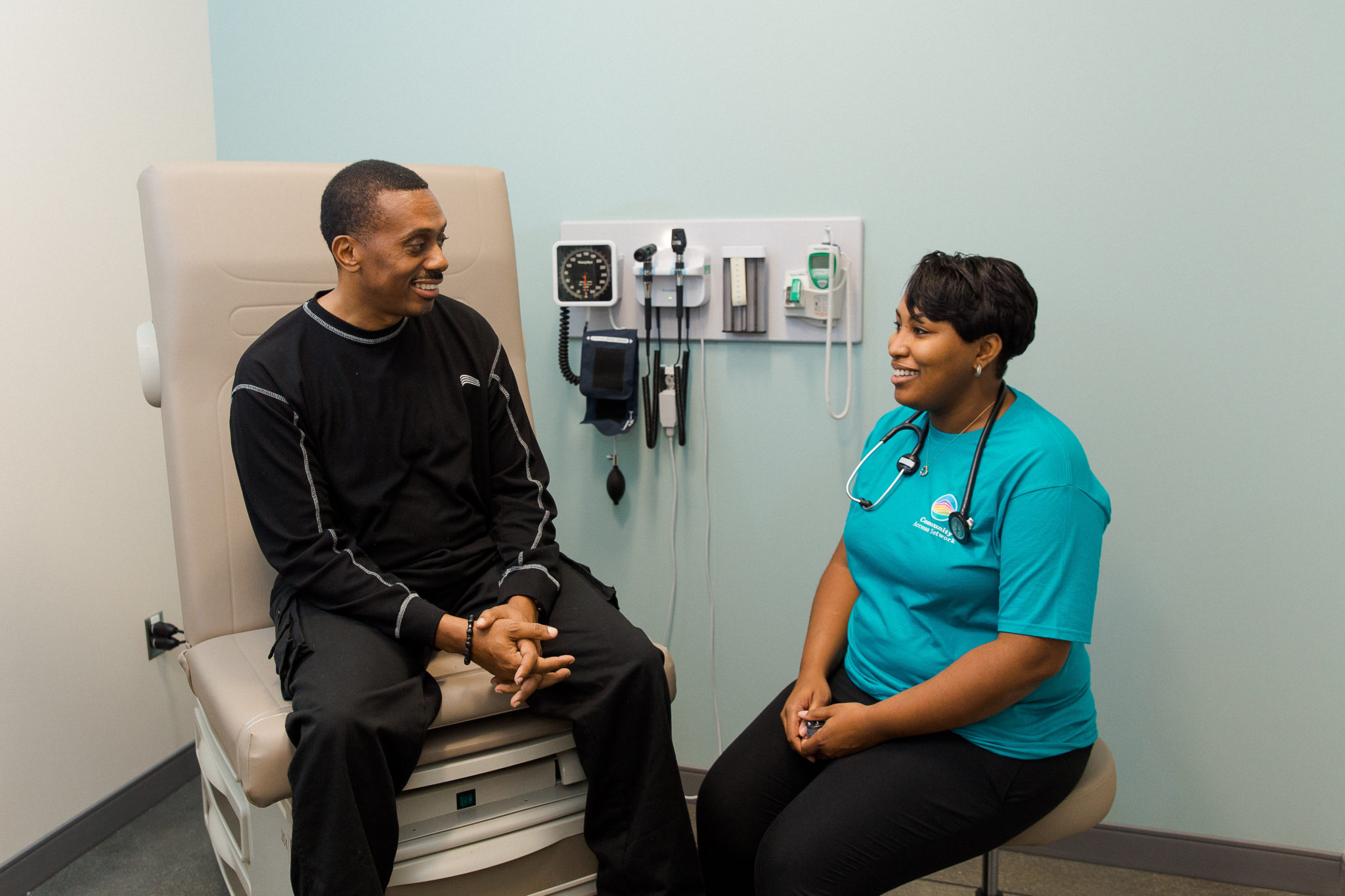a female nurse in a blue shirt consults with a male patient