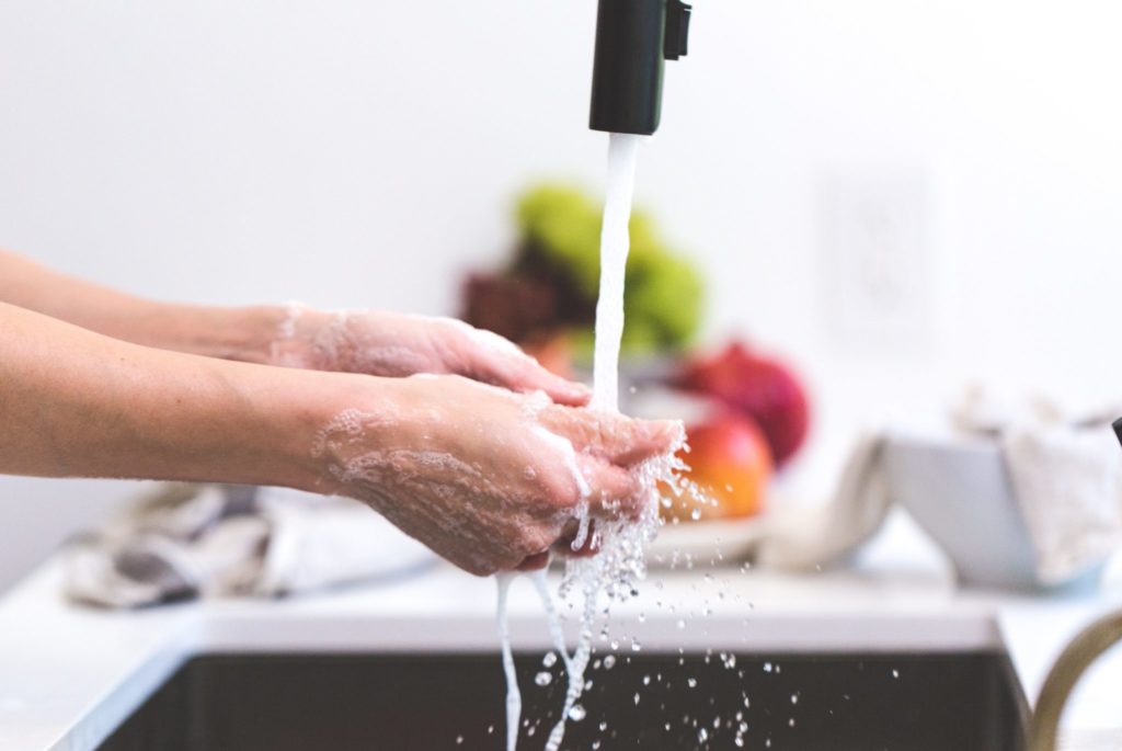 a woman's hands are washed with soap and water under a kitchen faucet