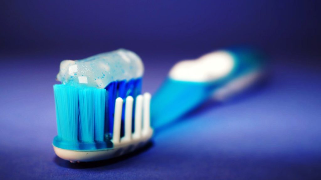 a blue and white toothbrush with toothpaste on top