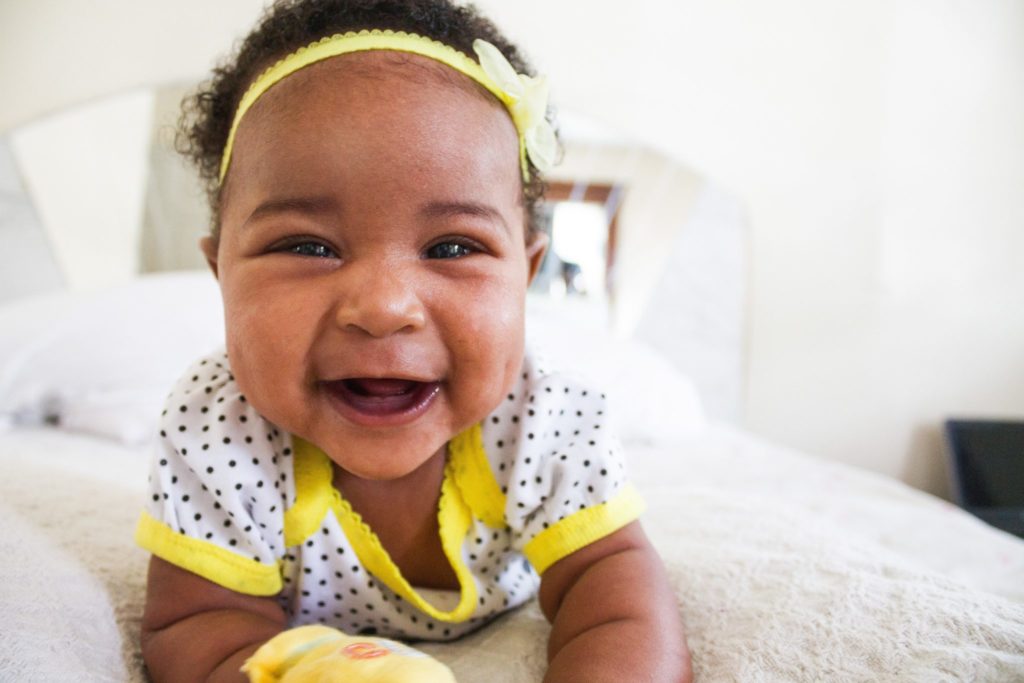 a smiling african american baby wearing a yellow headband