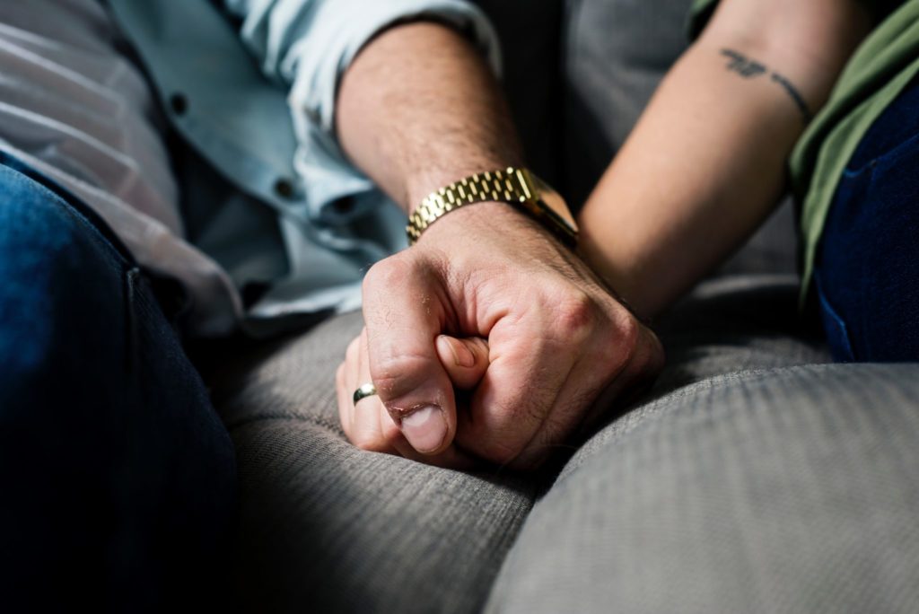 a man and woman hold hands on a sofa