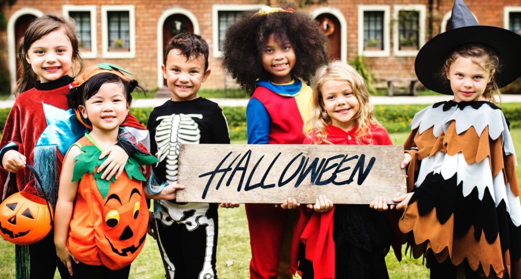 a group of children in halloween costumes hold a sign that reads "halloween"