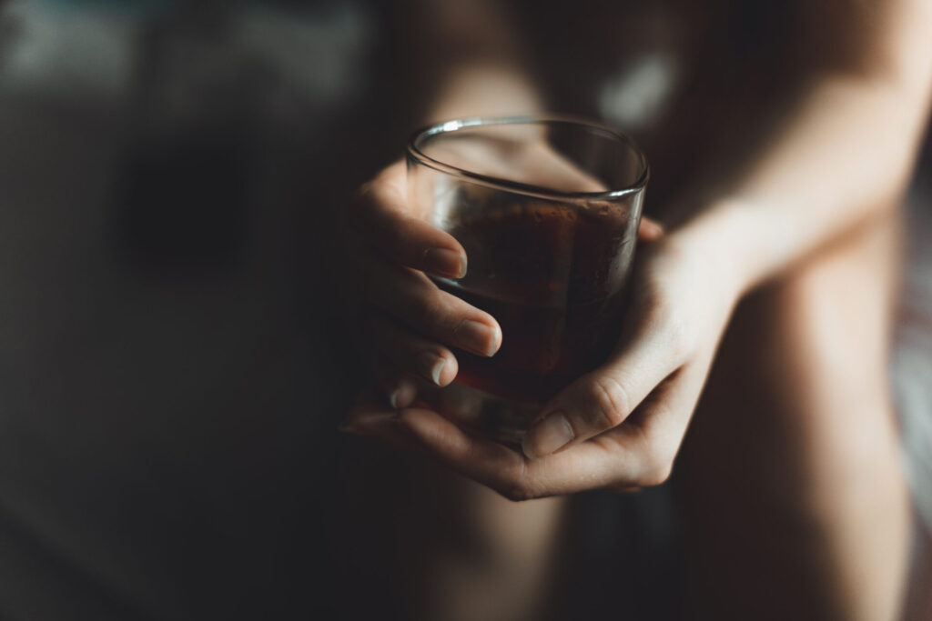 woman's hand with alcohol drink in glass