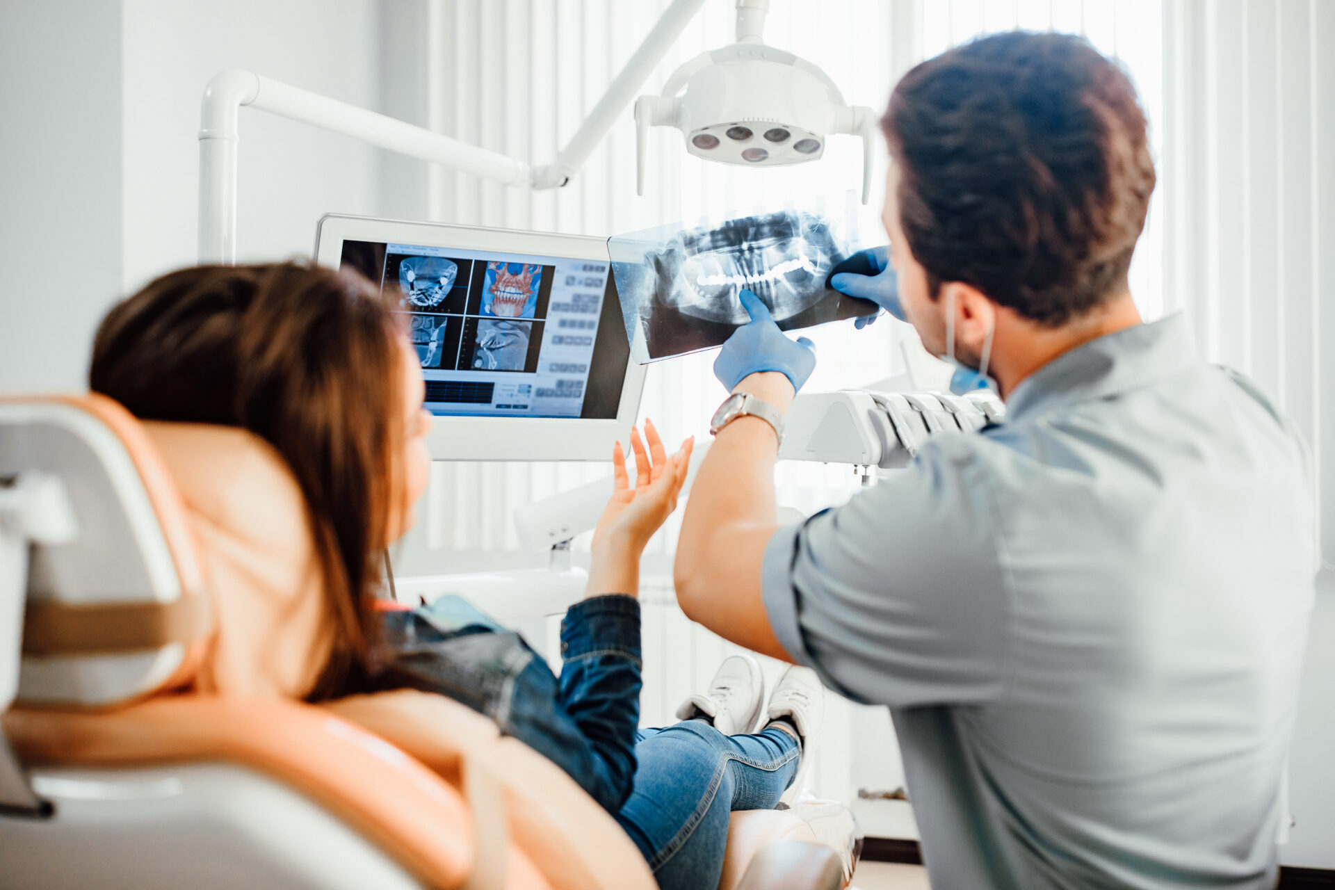 male dentist showing teeth x-ray to female patient at dental clinic office.