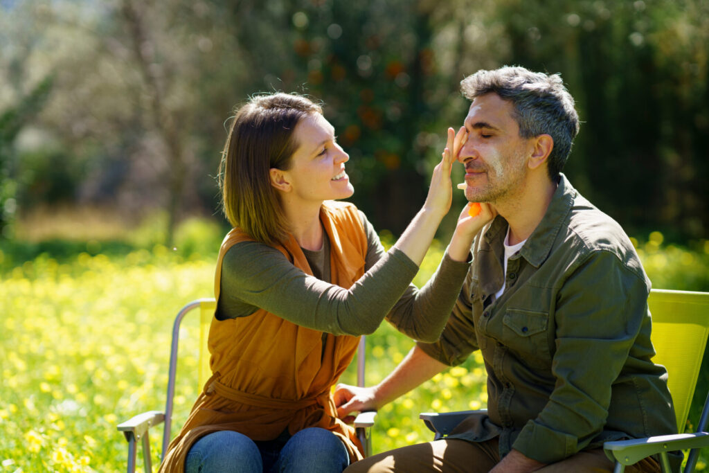 Young woman putting sunscreen on her boyfriend